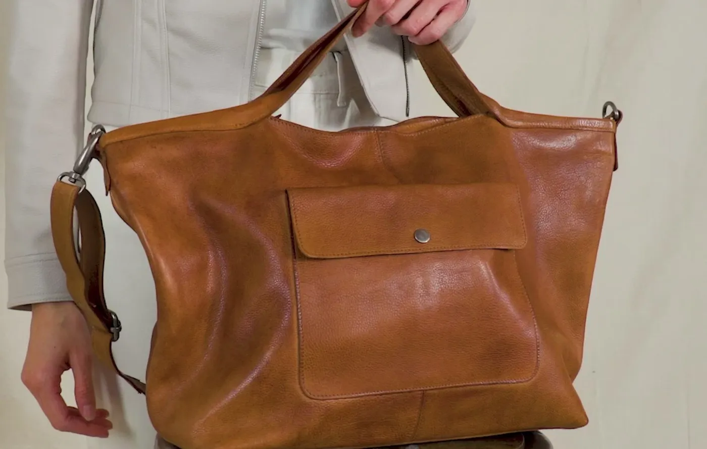 A cognac full-grain leather Colin bag held at the hip, from the Latico Colin product page.